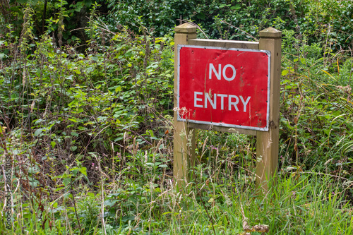 No entry sign in woodland in front of a hedge