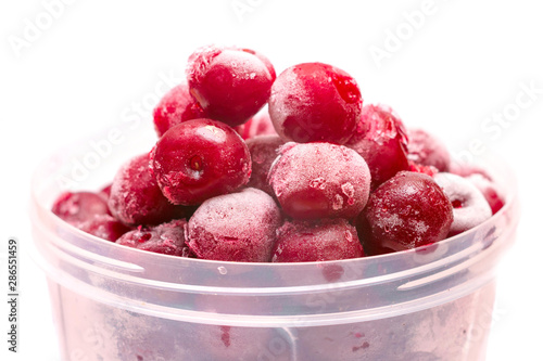 Bunch of winter cherries are isolated on a white background. Frozen cherries are in a plastic bucket. Red fruits is in a round plastic form.