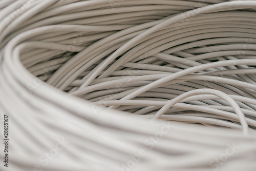 A rolled gray cable is a close up. A bunch of utp wires intertwined with each other. Abstract technological background texture. The concept of wired Internet communications.