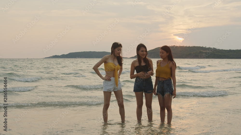 Group of Asian women talking together enjoy funny moment on beach, Beautiful female relax on beach near sea when sunset in evening. Woman travel on beach in summer concept.
