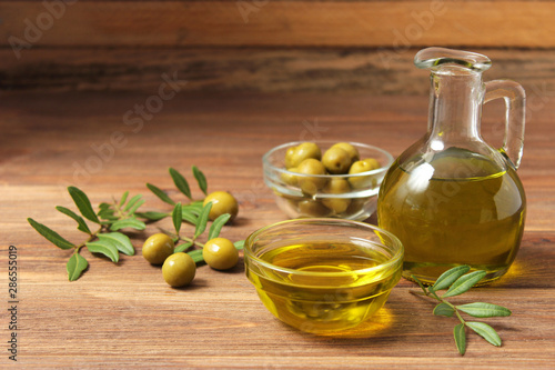 olive oil, green leaves and olives on the table.