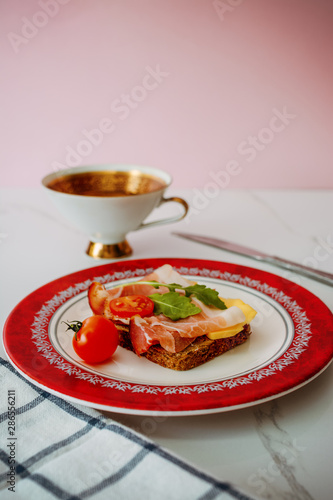slice of bread with smoked ham, cheese and tomatoes on red plate