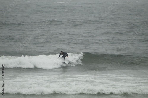 surfing the waves on the beach of Matosinhos in Porto, Portugal. August 2019