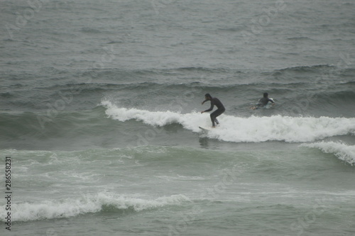 surfing the waves on the beach of Matosinhos in Porto, Portugal. August 2019