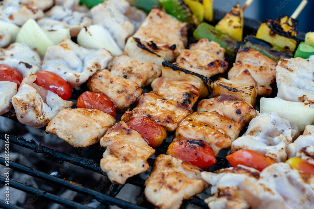 Skewers with pieces of grilled barbecue, green bell pepper, red tomato and meat for sell in street market, Thailand, closeup