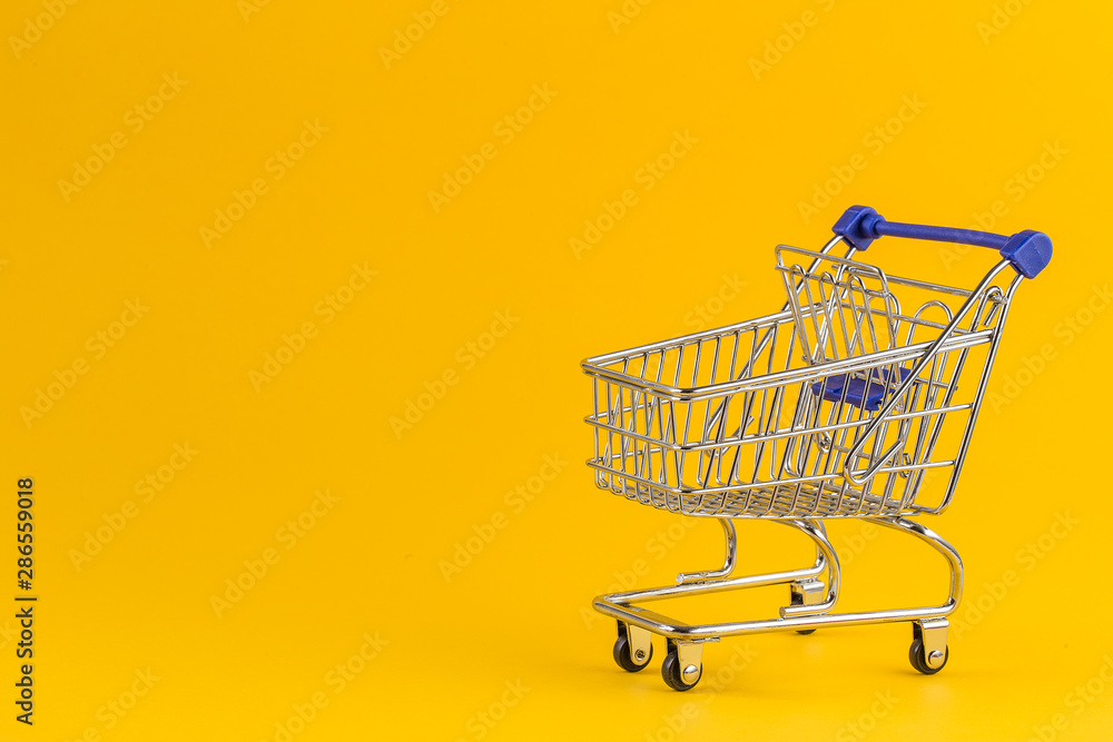 Shopping cart on bright yellow paper background Shopping cart on bright yellow paper background