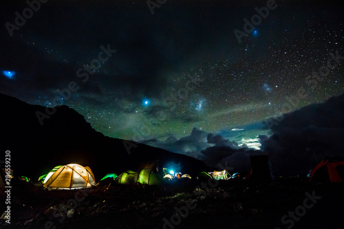 Pitched tents camping at the base of Mount Kilimanjaro at night under the stars