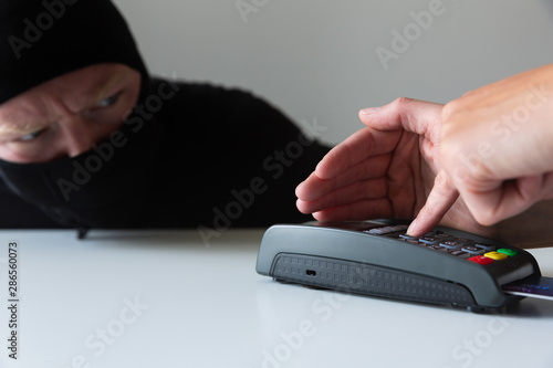 Фотография Thief is stealing pin code and identity on payment (pos) terminal machine