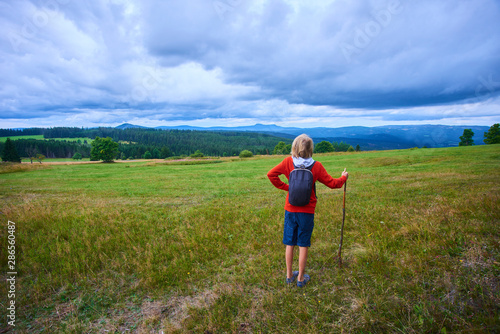 Little child boy with backpack hiking in mountains