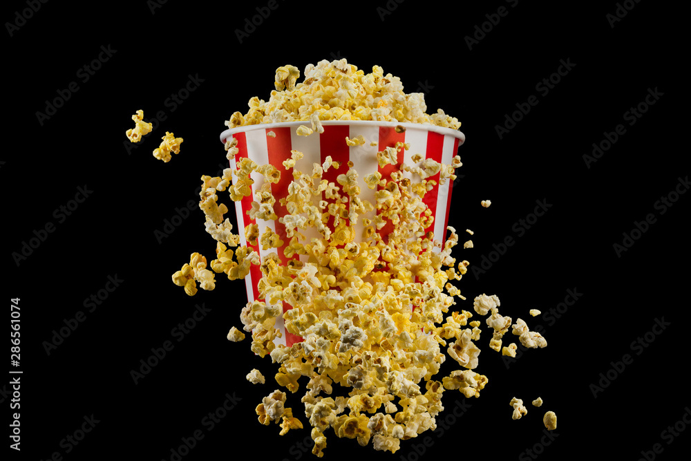 Flying popcorn from striped bucket isolated on black background Flying popcorn from striped bucket isolated on black background