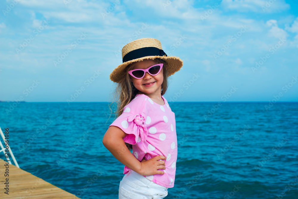 Happy smiling girl in straw hat posing at the beach