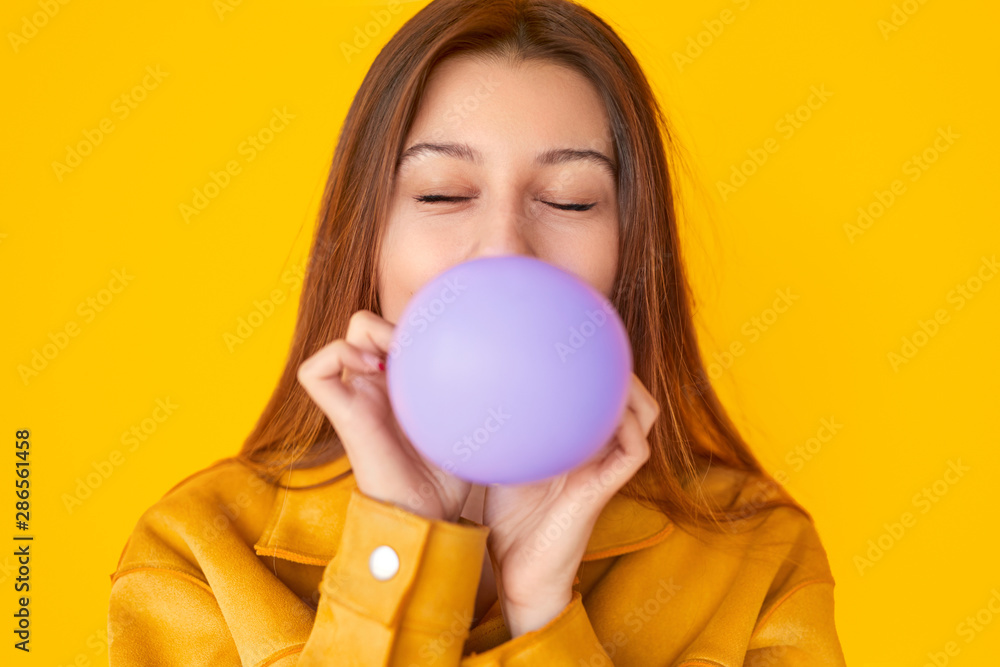 Young female blowing balloon with closed eyes