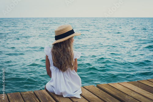 girl sitting on wooden bridge , looking at the sea © shapovalphoto