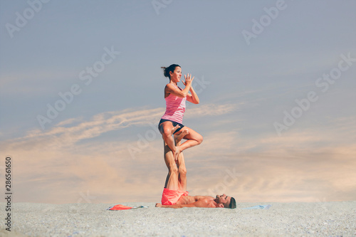 Young sporty woman practicing acroyoga at sunrise or sunset. © Global News Art