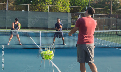 Men and women taking an outdoor tennis lesson