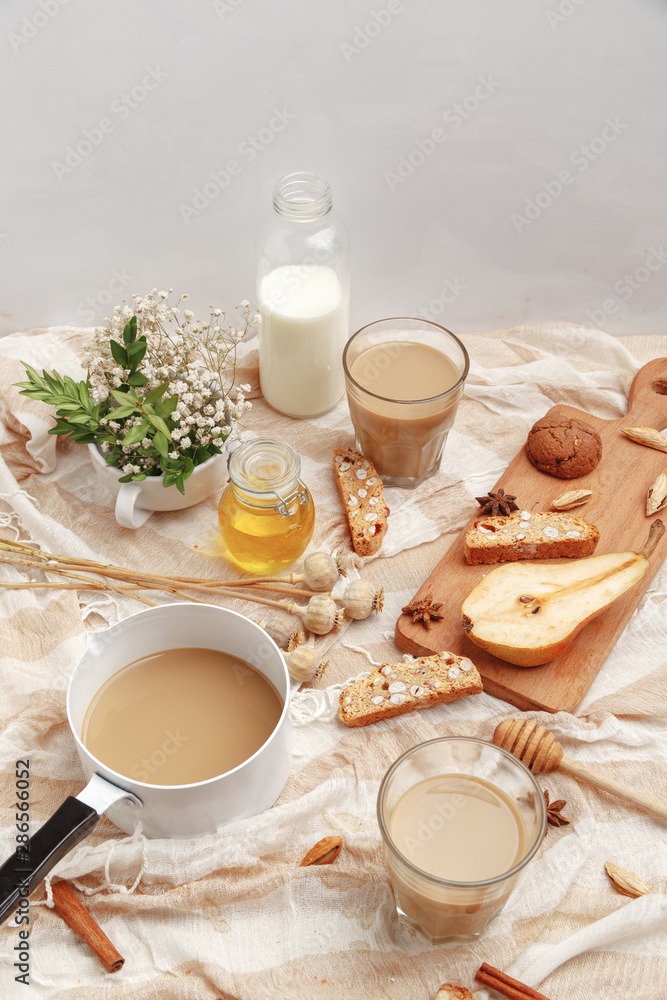 Coffee with milk, cookies, cinnamon and fruits on the tablecloth. Coffee with milk, cookies, cinnamon and fruits on the tablecloth.
