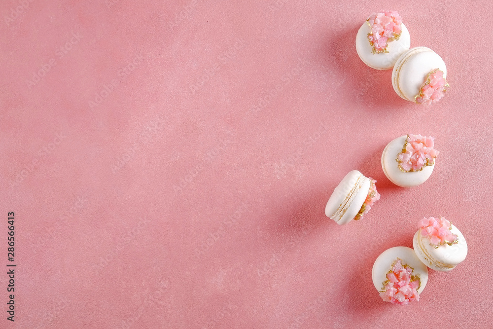 Minimalistic composition with bunch of white french macaron sweets with pink crystal shaped marmalade decoration over grunged concrete texture background. Top view, close up, flat lay, copy space. Minimalistic composition with bunch of white french macaron sweets with pink crystal shaped marmalade decoration over grunged concrete texture background. Top view, close up, flat lay, copy space.