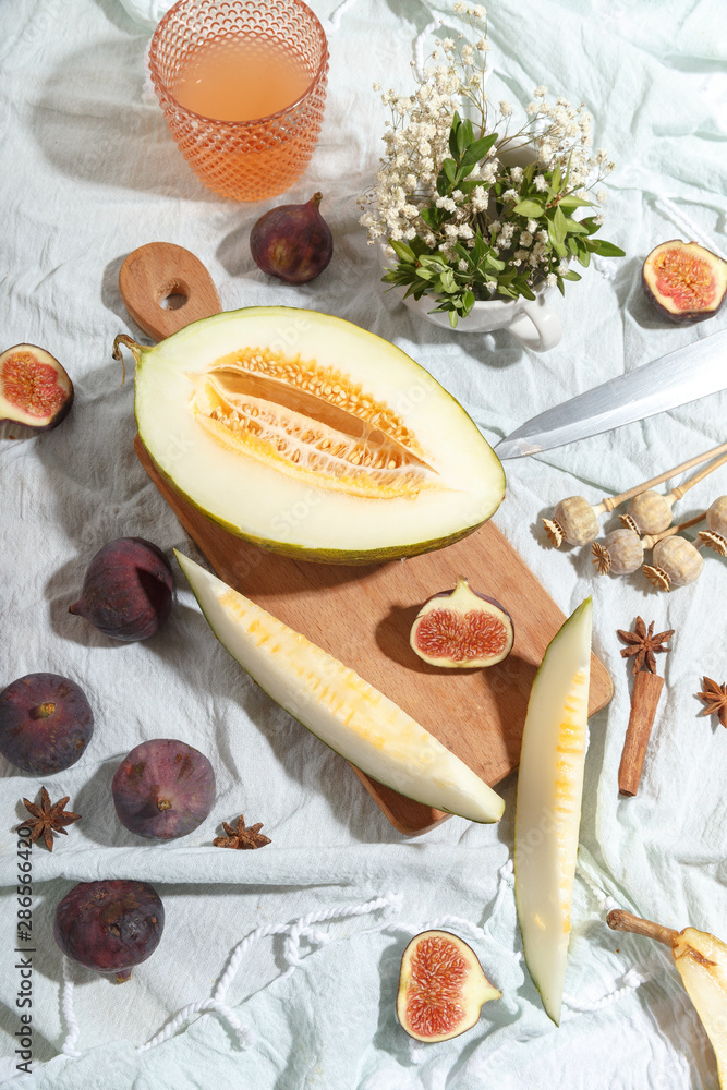 Cut appetizing ripe melon and drinks in stained-glass glasses on a table with a blue tablecloth.