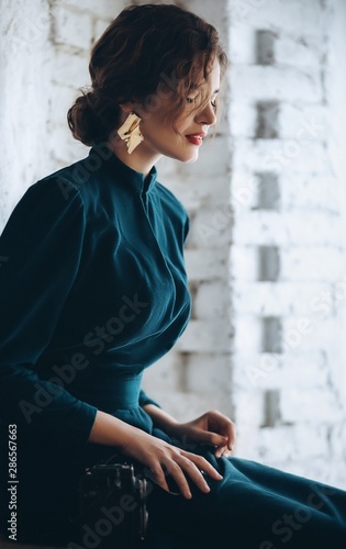 Portrait of beautiful young brunette woman with makeup in green fashion clothes