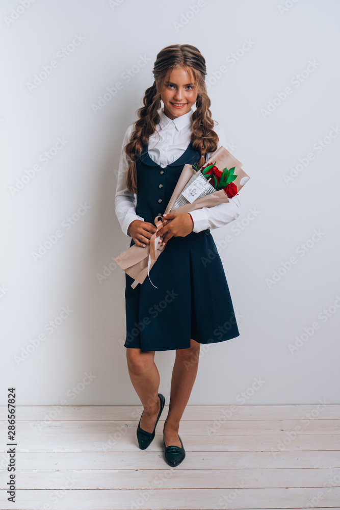 Schoolgirl posing with a bouquet of flowers. Girl in a school suit. Day of Knowledge. September 1.