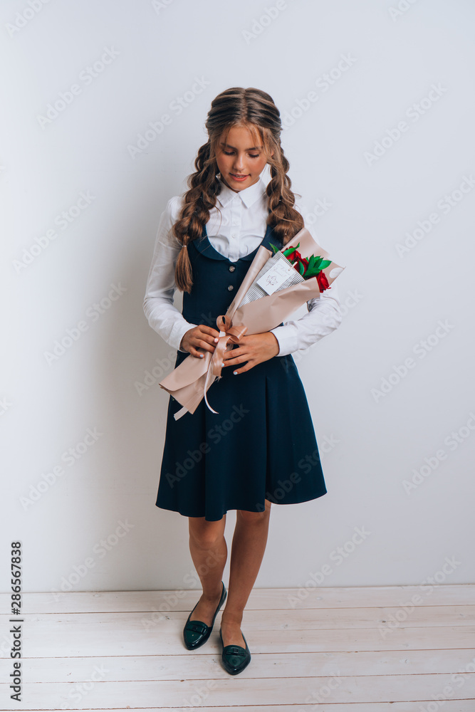 Schoolgirl posing with a bouquet of flowers. Girl in a school suit. Day of Knowledge. September 1. Schoolgirl posing with a bouquet of flowers. Girl in a school suit. Day of Knowledge. September 1.