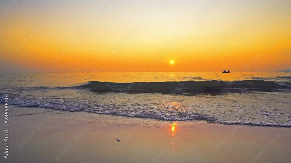 Small boat of refugees sail on sea horizon against sunset seen from beach splashed by waves Small boat of refugees sail on sea horizon against sunset seen from beach splashed by waves