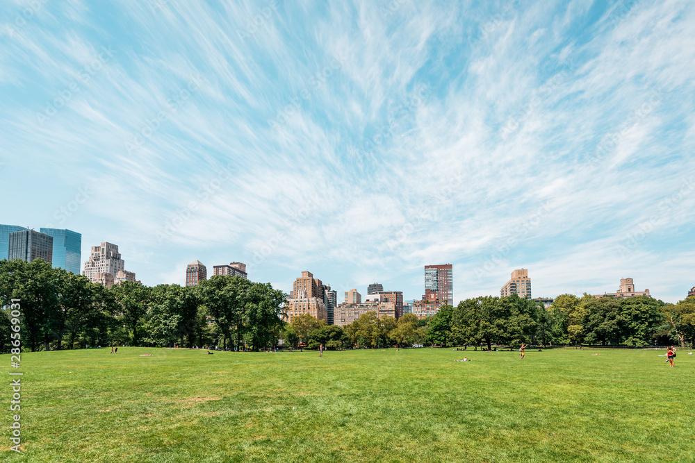 New York City/ Manhattan, NYC/ USA - 08 21 2017: Central Park on a sunny day with some clouds over the amazing skyline skyscraper of Manhattan CBD in Big Apple New York City/ Manhattan, NYC/ USA - 08 21 2017: Central Park on a sunny day with some clouds over the amazing skyline skyscraper of Manhattan CBD in Big Apple
