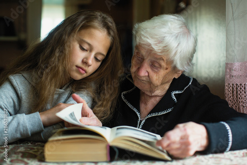 An elderly woman is reading a book to her beloved granddaughter.