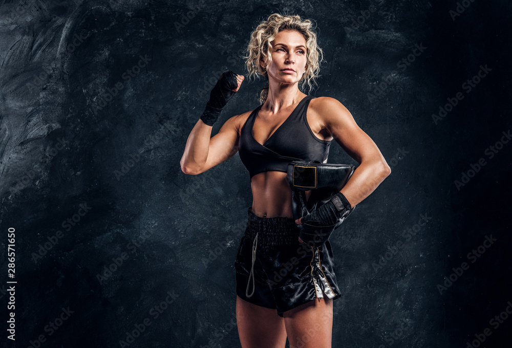 Portrait of powerful strong female boxer in red gloves over dark background. Portrait of powerful strong female boxer in red gloves over dark background.