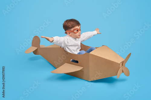 Little aviator flying in carton plane