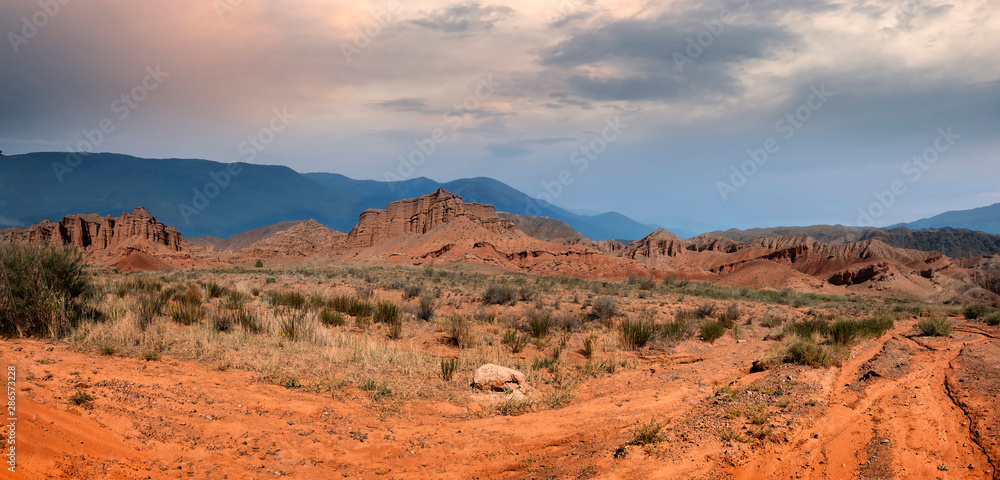 panorama of fantastic clay castles in the sandy desert of the red canyon Konorchek, in Kyrgyzstan on the Sunset