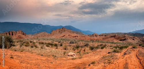 panorama of fantastic clay castles in the sandy desert of the red canyon Konorchek, in Kyrgyzstan on the Sunset
