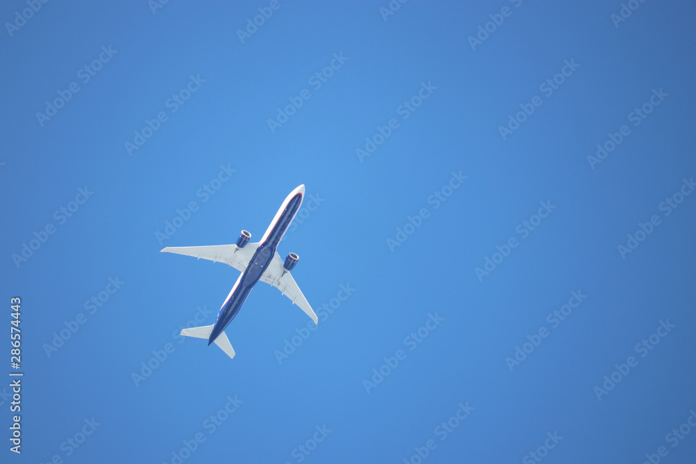 Airplane flying in the clear blue sky, bottom view. Commercial plane taking off Airplane flying in the clear blue sky, bottom view. Commercial plane taking off