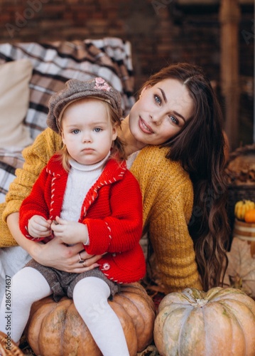 Beautiful baby girl in autumn garden with mother