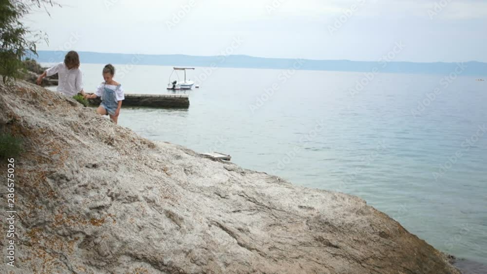 Boy and girl walk on a rocky seashore, first love, romantic walk, summer vacation Boy and girl walk on a rocky seashore, first love, romantic walk, summer vacation