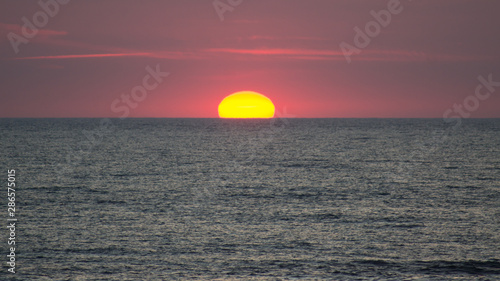 Fototapeta Naklejka Na Ścianę i Meble -  The setting sun touches the red horizon.