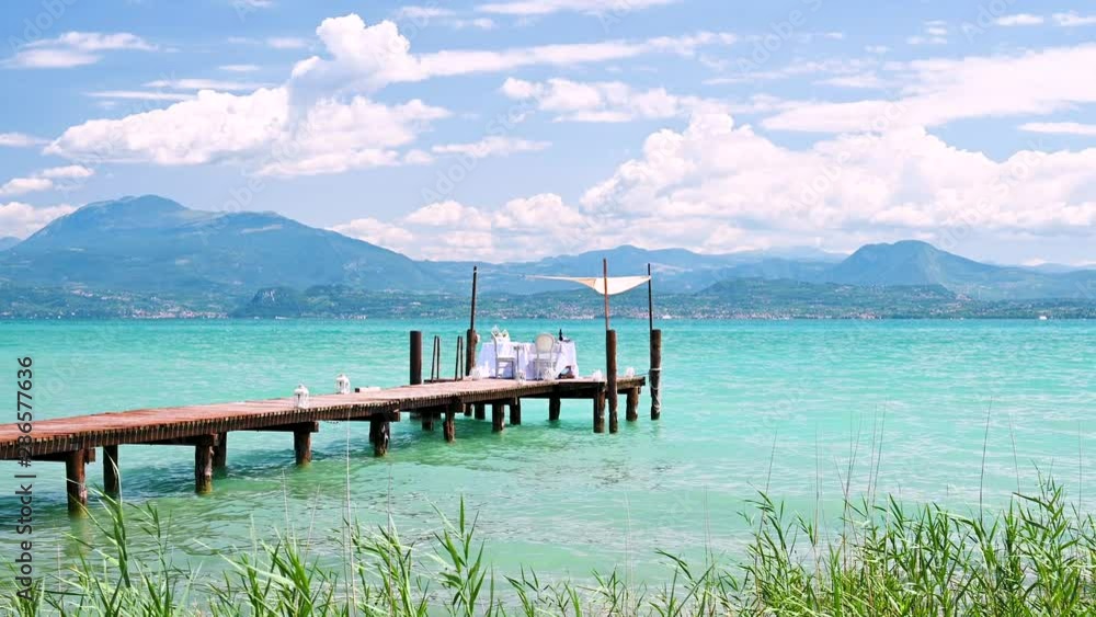 Served table for the holiday. Romantic dinner on the shore of a blue lake in the mountains. Luxury vacation. Mountains and lake in italy. Served table for the holiday. Romantic dinner on the shore of a blue lake in the mountains. Luxury vacation. Mountains and lake in italy.