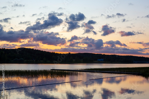 Sunset at the lakeside in Finland during summer evening. Glowing orange horizon.
