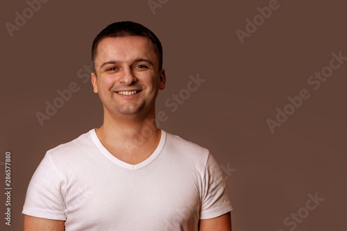 Fotografija Smiling man in white t-shirt. Gray background.