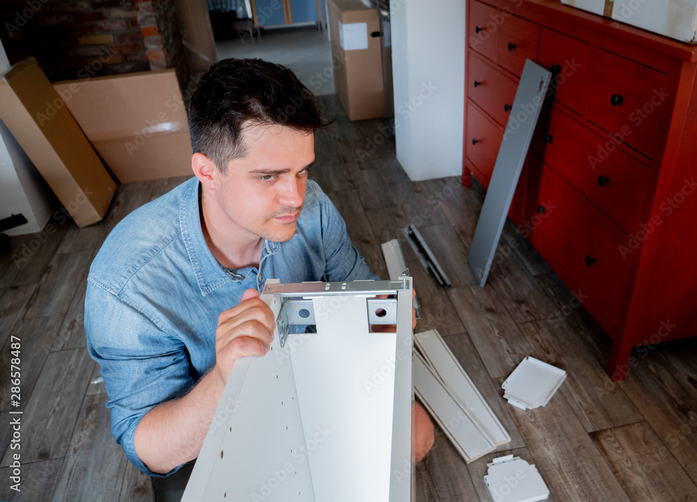 Obraz premium Young man with screwdriver instaling a furniture