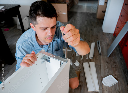 Wallpaper Mural Young man with screwdriver instaling a furniture Torontodigital.ca
