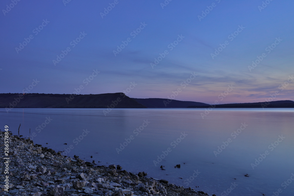 night long exposure landscape photography of national park scenic view with stone waterfront and lake smooth water foreground and hill land horizon background in silence peaceful atmospheric time