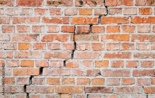 Texture of old weathered brick wall with long crack.