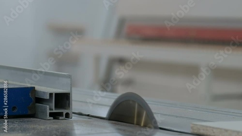 Machine for cutting sheet material. Circular saw cuts a piece of white laminated particleboard. Hands of a joiner close-up. Worker in the furniture industry.