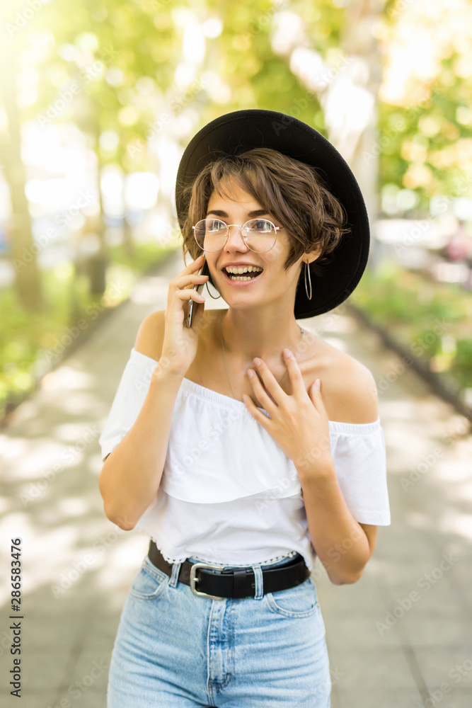 Beautiful young smile woman smiling and talking on cell phone on sunny street. Beautiful young smile woman smiling and talking on cell phone on sunny street.