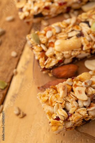 granola bars and nuts on a wooden background with space for design, vertical photo, diet, proper nutrition