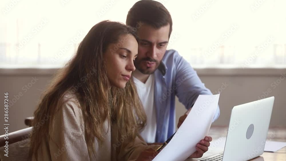 Couple reading agreement analyzing loan contract using online e-banking Couple reading agreement analyzing loan contract using online e-banking