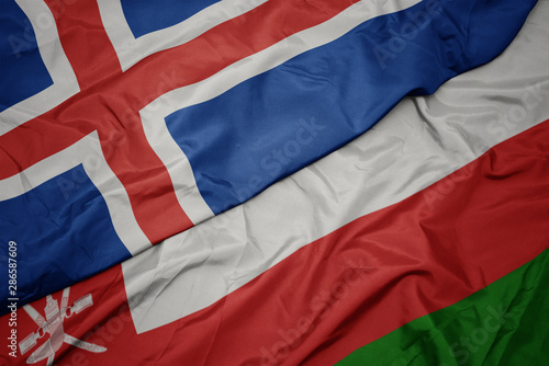 waving colorful flag of oman and national flag of iceland.