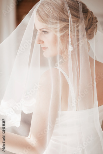 Beautiful blonde bride with stylish make-up in white dress