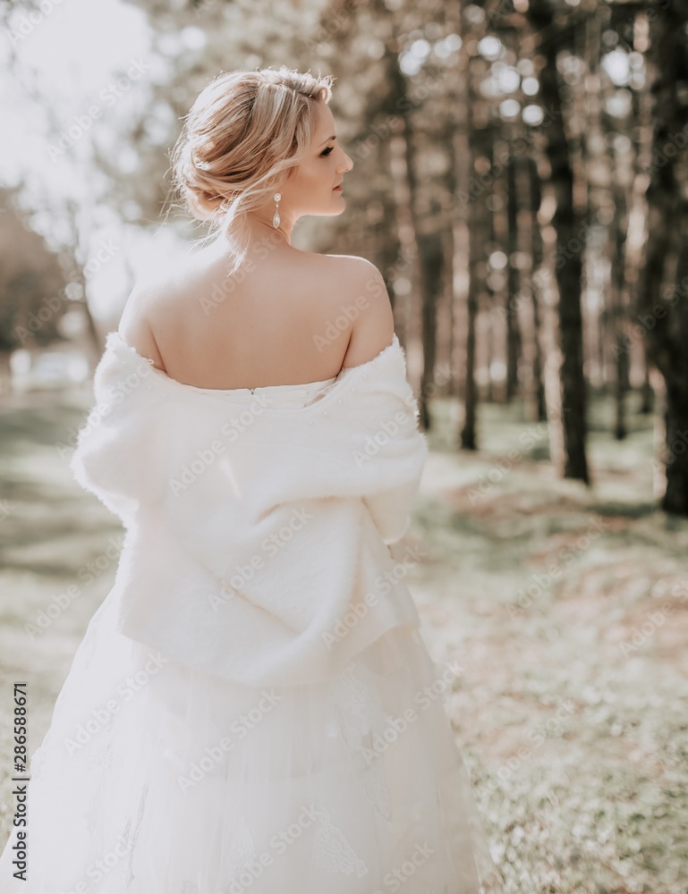Beautiful blonde bride with stylish make-up in white dress in spring garden Beautiful blonde bride with stylish make-up in white dress in spring garden